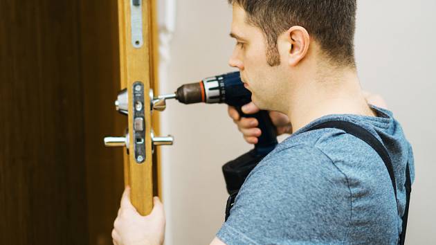 a man using a drill to install or enable a door lock, illustrating the installation process