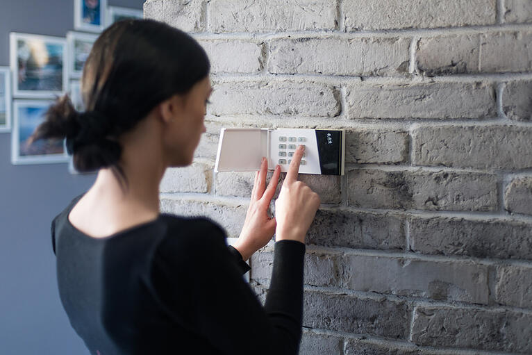 A women professional locksmith installing a high-security lock on a residential brick wall in North Atlanta.